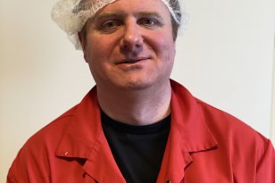 Portrettfoto av mann med hårnett og rød arbeidsfrakk