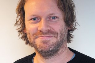 Professor Anders Nordahl-Hansen En mann i midten av 40-årene med lys hud og blå øyne ser rett mot kamera. Han har kort til middels langt, brunt, litt bølgete hår og et skjegg som dekker underkjeven og kinnene. Han smiler svakt. Han har på seg en svart, ribbestrikket genser over en lys blå t-skjorte. Bakgrunnen er enkel og lys.
