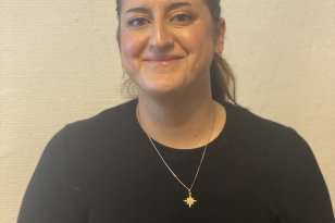 Kvinne med langt mørkt hår og svart genser smiler
