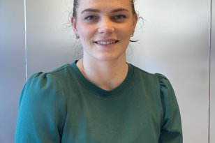 Ung kvinne med grønn kjole smiler mot kamera
