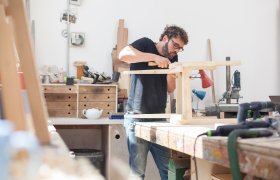 En møbelsnekker lager en stol på en benk