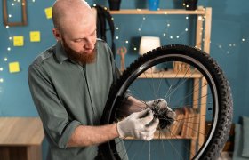 En mann skrur på et sykkelhjul