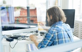 En mann sitter foran en pc skjerm