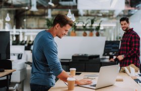 Bilde viser to menn som smiler i et kontorlandskap