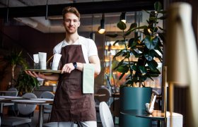 En servitør står med en serveringsfat med glass