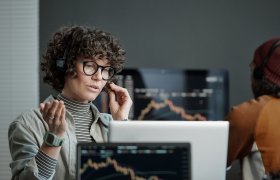 Bilde av en kvinne som sitter foran en PC og snakker i et headset