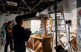 To kameramenn filmer en programleder i et tvstudio