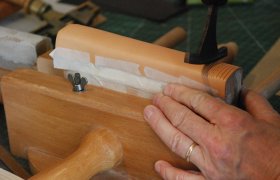 En håndbokbinder preger ryggen på et bokomslag av skinn