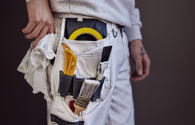 Nærbilde av en arbeidsbukse med maleutstyr.