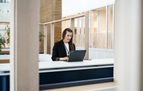 Kontor- og administrasjonsmedarbeider Tinecke Torsvik skriver på en data i et åpent landskap.