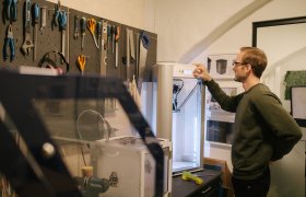 En mann stiller inn en 3d printer