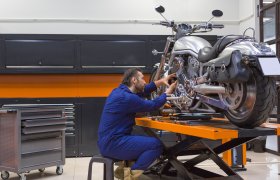 En motorsykkelmekaniker reparerer en motorsykkel som står på et bord