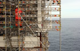 To stillasarbeidere på et stillas rundt en oljeplattform