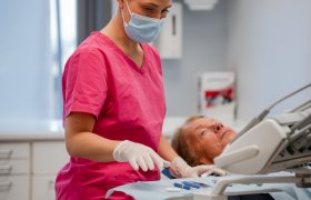 En tannpleier tar etter et instrument på et bord