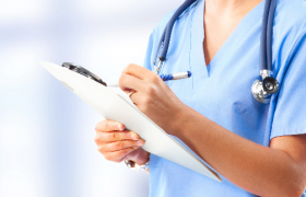 Sykepleier i blå skjorte med stetoskop rundt halsen. 