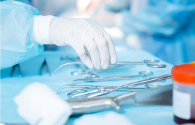 En hånd med en plasthanske, holder en kirurgisk saks.