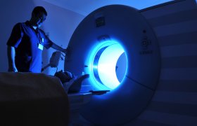 Onkologen fører ein person inn i ei strålemaskin