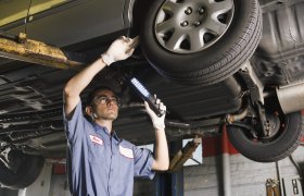 Hjulutrustningsreparatøren undersøker understellet på en bil.