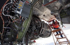 Flystrukturmekanikeren står i en stige og skrur på en motor på et passasjerfly.