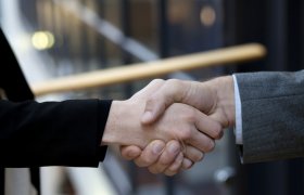 Megler tar en person i hånda. 