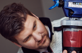 En mann ser på en malesprøyte med rød maling