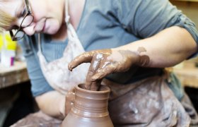 Kvinnelig kunsthåndverker lager leirvase.