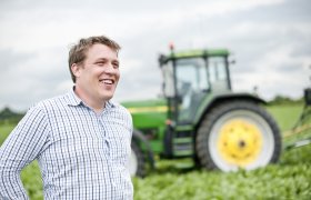 Mann står foran traktor. 