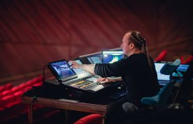 Lydtekniker justerer lys i teatersal.