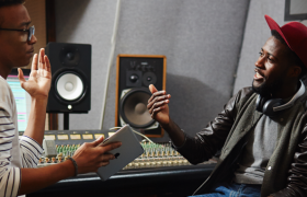 To personer diskuterer foran et miksebord