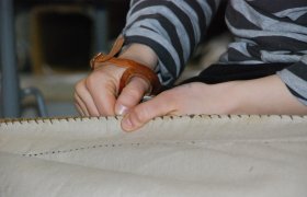 En seilmaker syr sammen et seil.