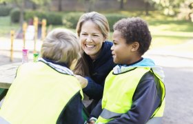 SFO-leder i samtale med barn i skolegården.