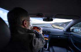 Sjåfør bak rattet i personbil.