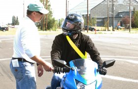 Trafikklærer underviser motorsyklist.