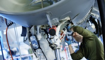 En avioniker, eller flymekaniker, reparerer et fly på Bodø Hovedflystasjon.
