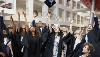 Ferdigutdannede universitetsstudenter kaster hattene sine opp i lufta.