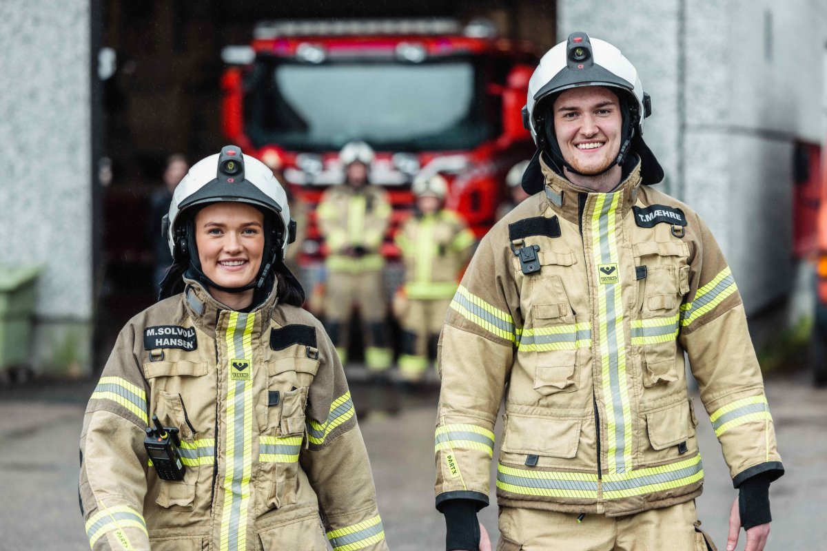 En mannlig og en kvinnelig brannkonstabel smiler mot kamera