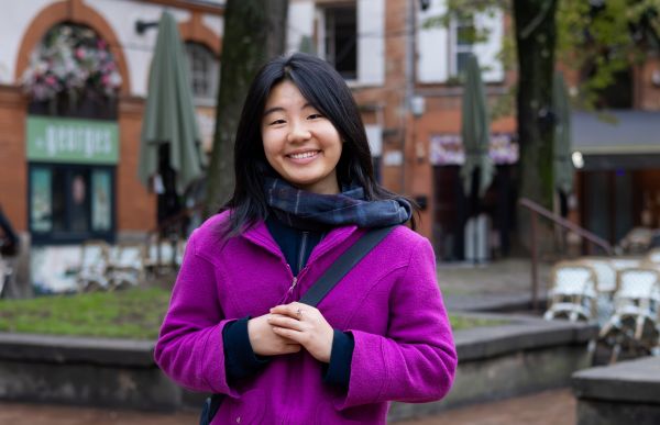 En ung dame smiler. Hun er ute.